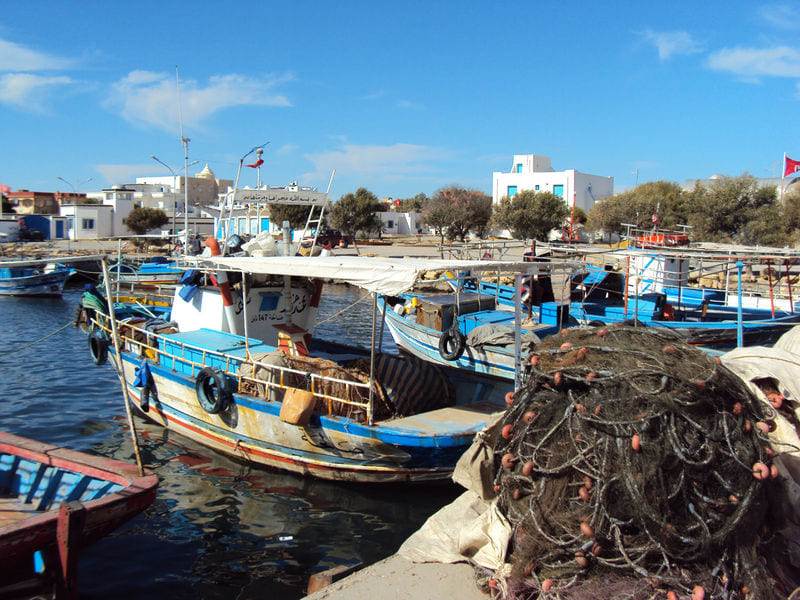 Barques de pêche bleues et filets dans l’ancien port de Béni Khiar