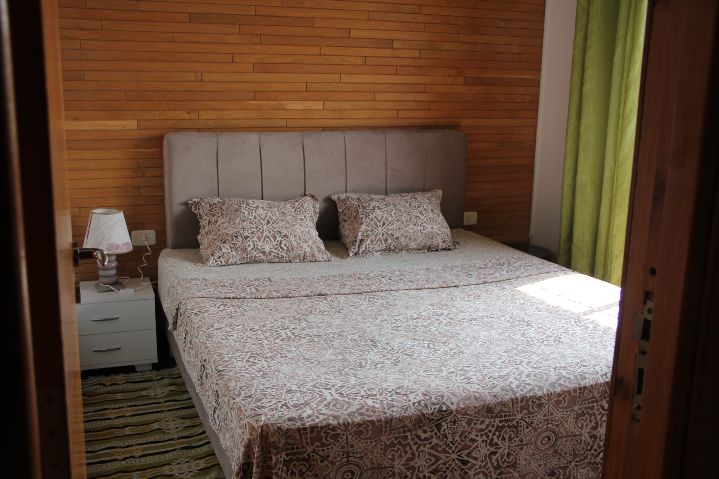 Chambre double du Chalet Essanya : lit king size, tête de lit capitonnée et murs en bois