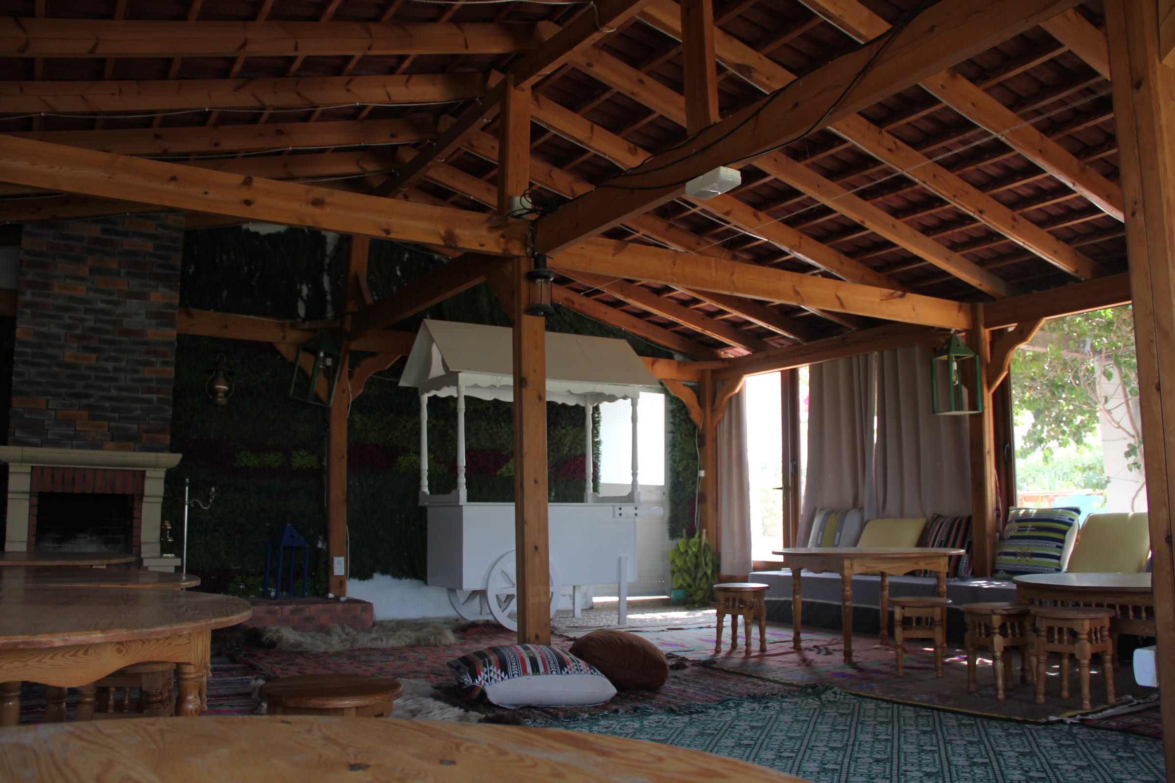 Espace commun de 100 m² sous charpente en bois, tapis traditionnels et cheminée